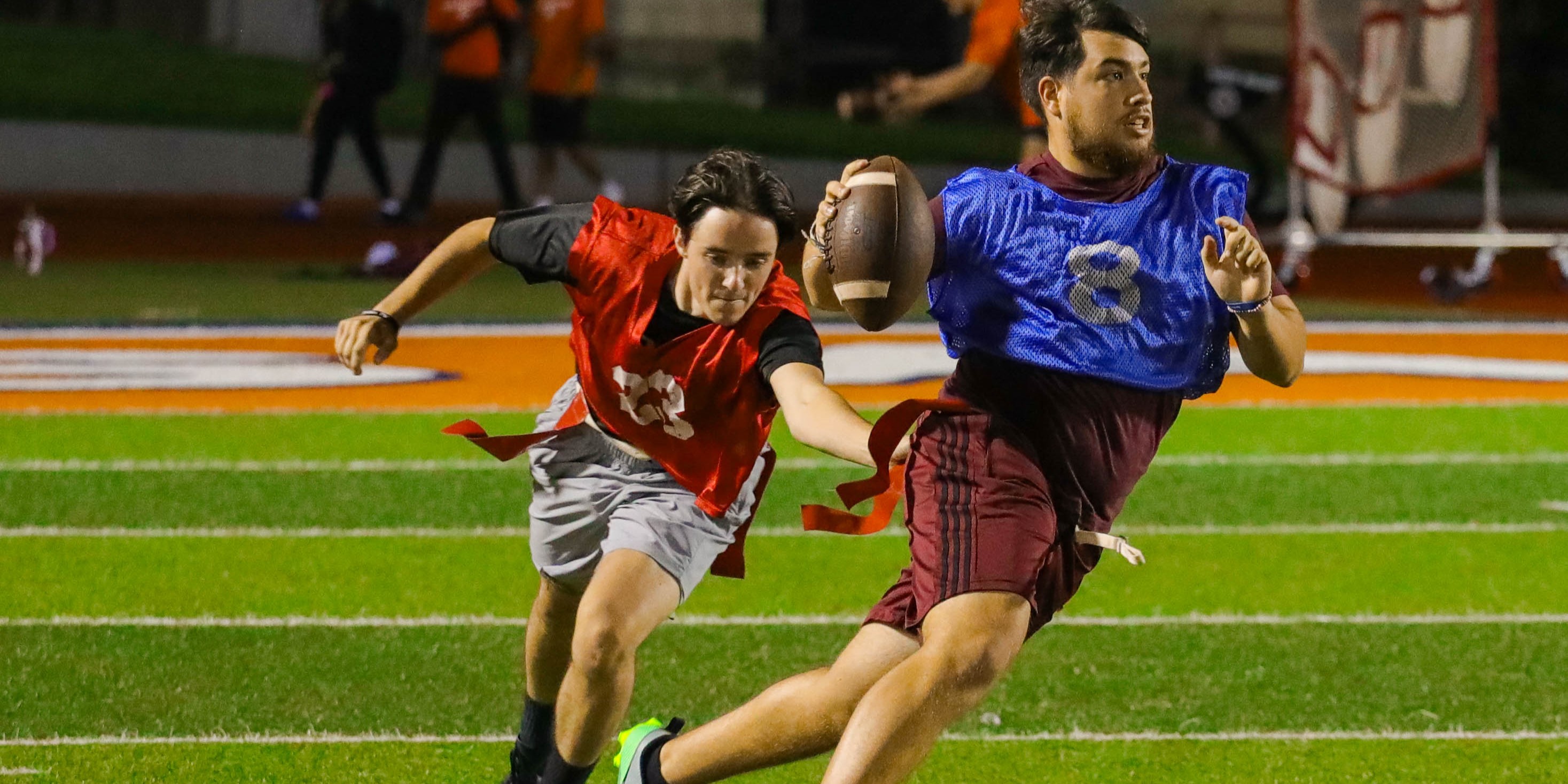 flag football players chasing one another to pull flag
